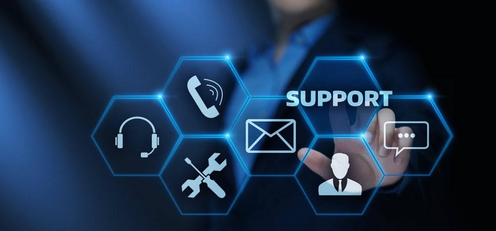 A person in a suit points at digital hexagonal icons representing IT support services. Icons include a phone, email, headset, wrench and screwdriver, user profile, and chat bubble. The word "SUPPORT" is prominently highlighted.