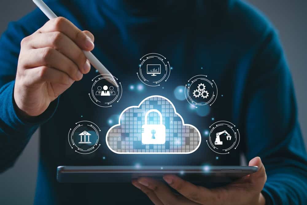 A person uses a stylus on a tablet, interacting with a secure cloud icon, symbolizing Cloud Services and Migration with tech elements.