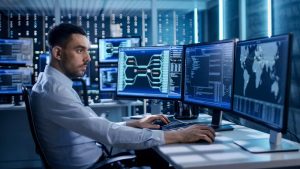 A man sits at a desk, analyzing cybersecurity data on multiple screens in a dimly lit, high-tech room. Cybersecurity Tips flash on display.