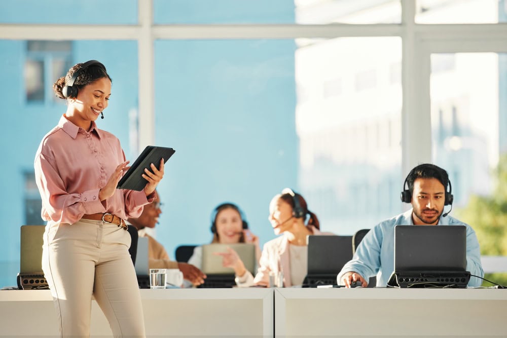 Happy woman call center manager holding a tablet while assisting customers, representing CTS Computers services in Illinois and Indiana.