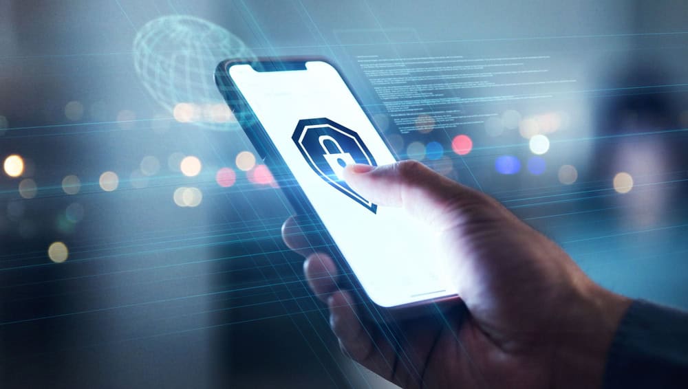 A person’s hand holds a smartphone displaying a padlock icon, symbolizing security or data protection, with a blurred city background and digital elements overlayed.