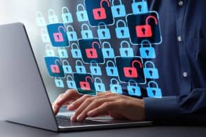 A person typing on a laptop with multiple digital padlock icons, some locked and some unlocked, floating above the keyboard, symbolizing cybersecurity and data protection.